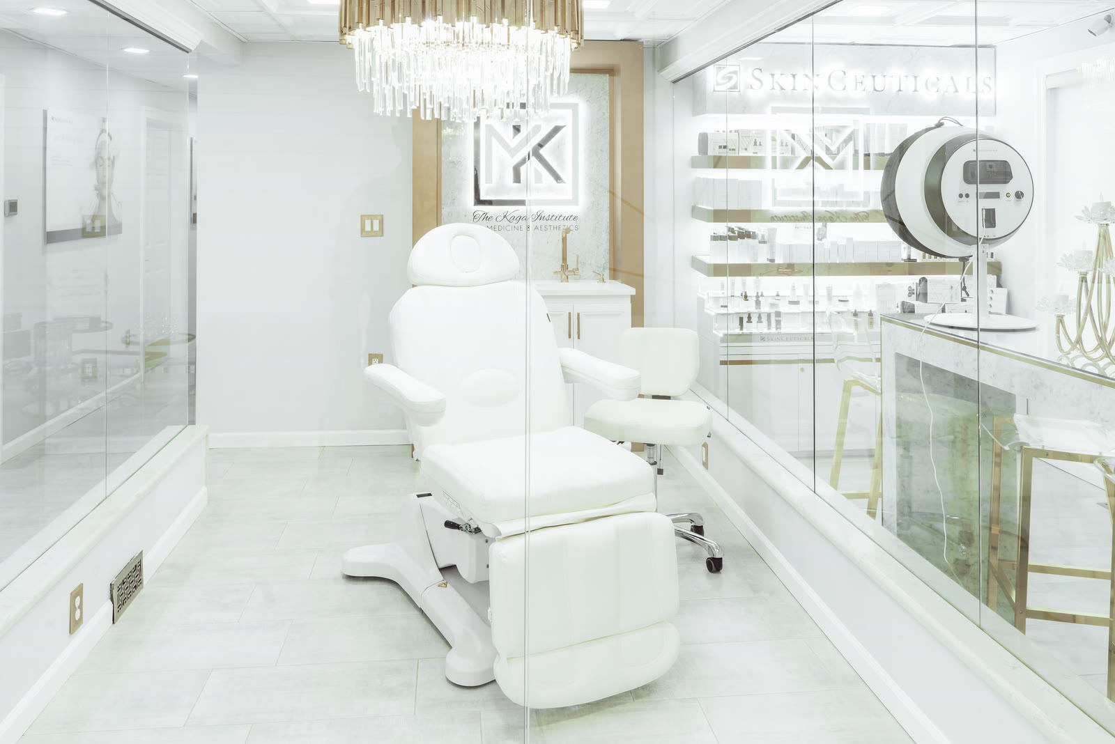 White treatment chair in a glass-walled suite under a chandelier