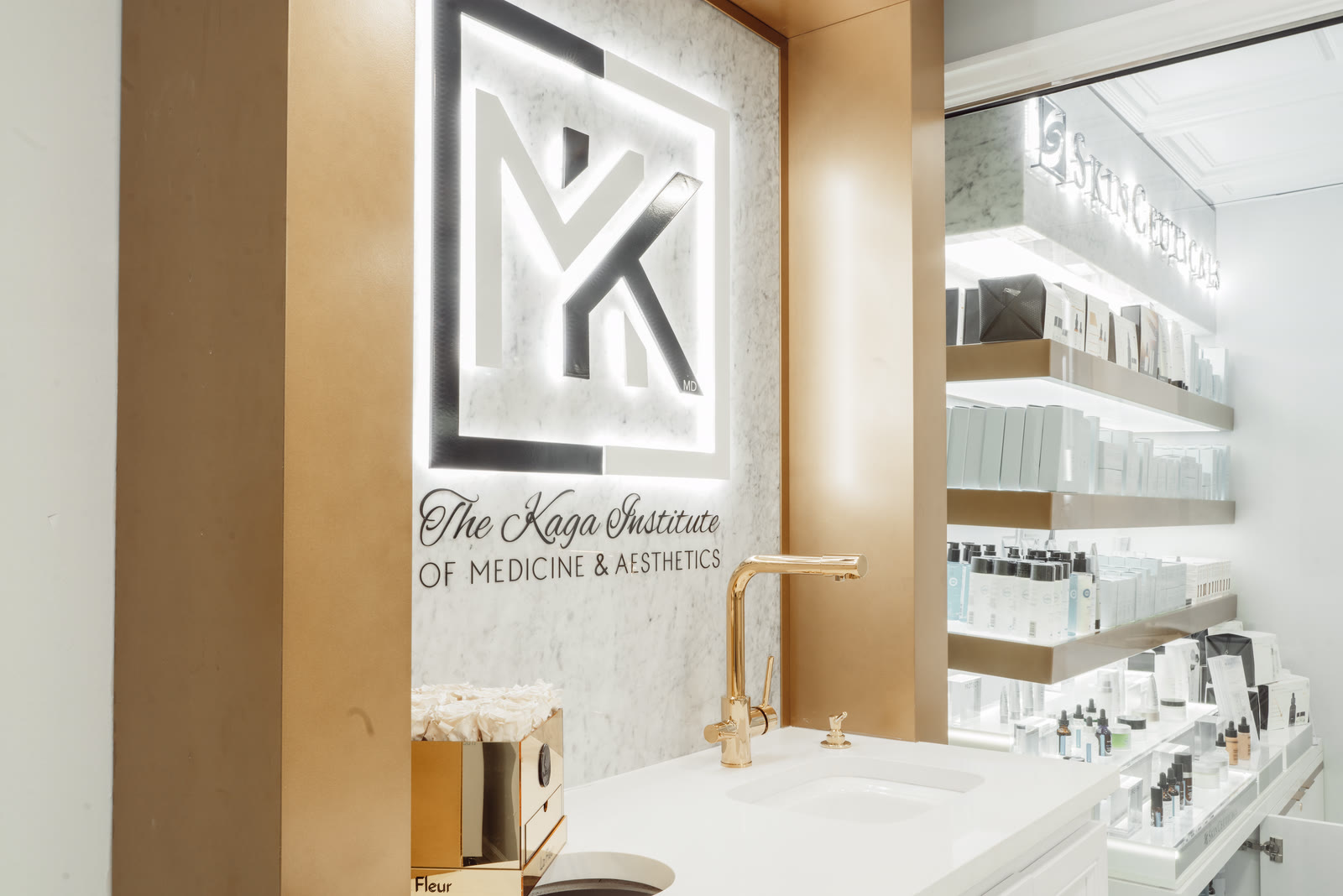 Illuminated Kaga Institute monogram on a marble and brass wall