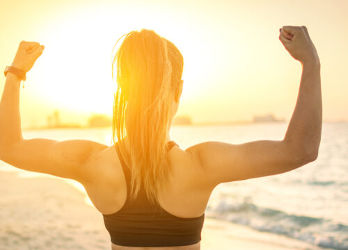 Photo of a woman flexing her muscles at the beach