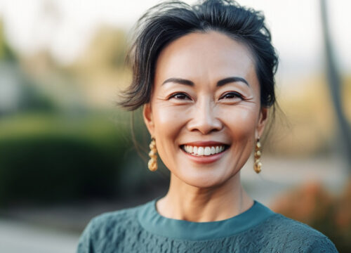 Photo of a middle aged smiling woman outside wearing a green sweater