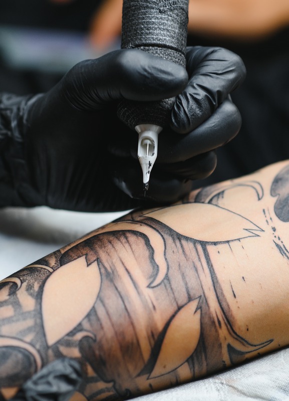Photo of a tattoo artist tattooing a man's arm