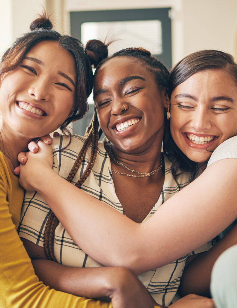 Photo of three happy female friends hugging