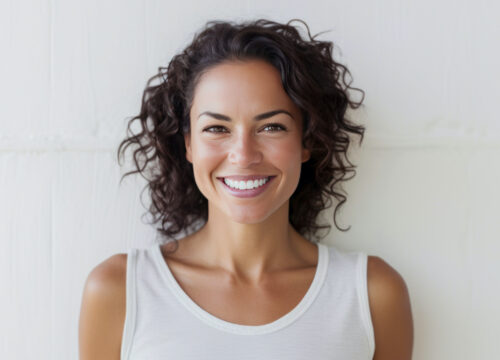 Photo of a smiling woman with brown, curly hair and great skin