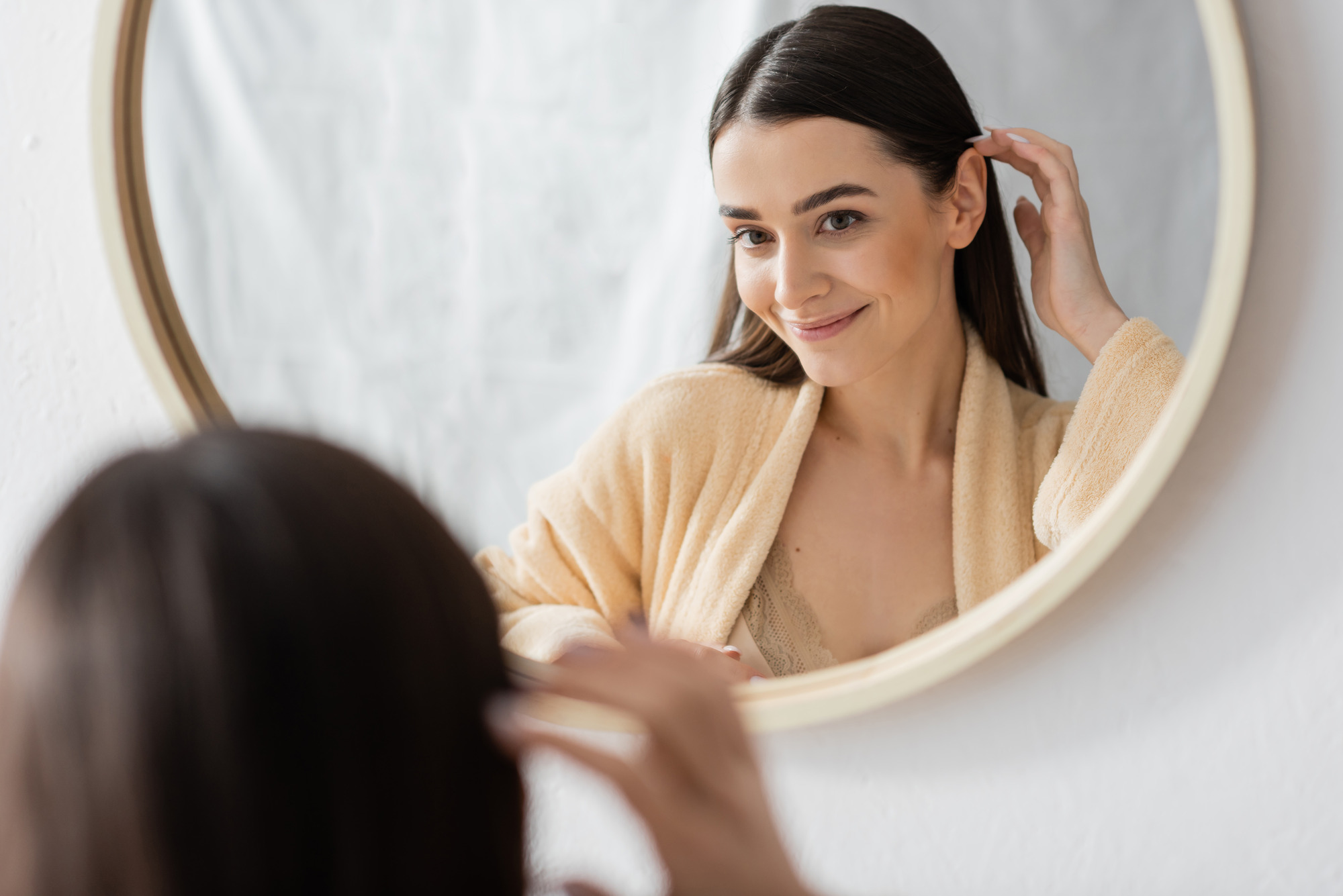 Photo of a brunette woman looking at her skin in the mirror