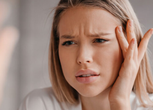 Photo of a woman looking at her frown lines in the mirror